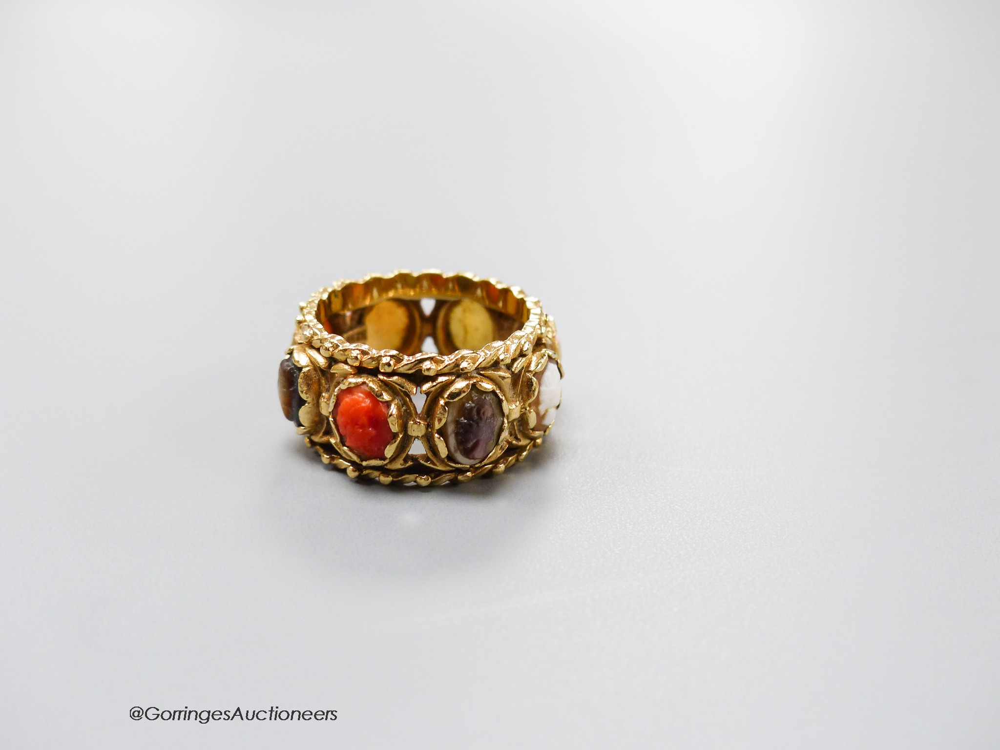 A 14kt yellow metal and multi cameo stone set eternity ring, including shell and coral, size P, gross weight 9.2 grams.